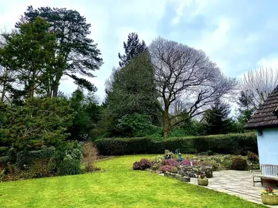 a garden with a bench and flowers and trees at A spacious hidden gem with hot tub, lovely garden & views in Kington