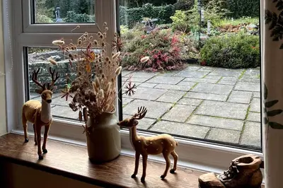 a window sill with two deer figurines and a vase at A spacious hidden gem with hot tub, lovely garden & views in Kington