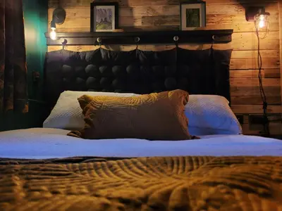a bedroom with a large bed with a wooden wall at Kettle Tree Cabin in Welshpool