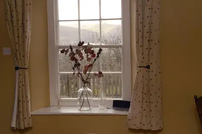 a window with a vase with flowers in it at Glan y Morfa Welsh farmhouse overlooking Dyfi Estuary Rated 4 star Visit Wales in Pennal