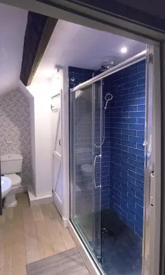 a bathroom with a shower with a blue tile wall at Glan y Morfa Welsh farmhouse overlooking Dyfi Estuary Rated 4 star Visit Wales in Pennal
