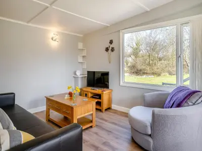 a living room with a couch and a television at Tynrhos Lake View in Cilcennin