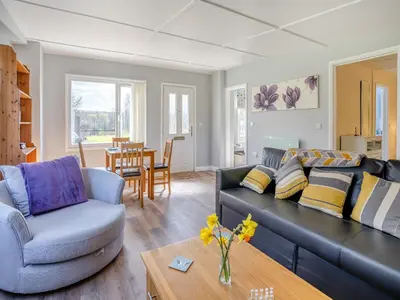 a living room with a black couch and a table at Tynrhos Lake View in Cilcennin