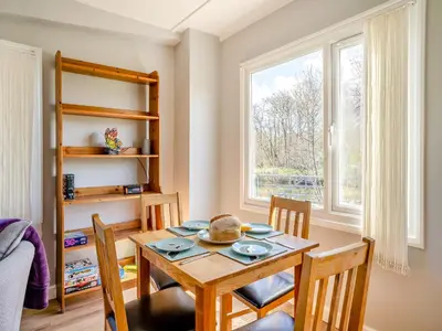 a dining room with a table and chairs and a window at Tynrhos Lake View in Cilcennin