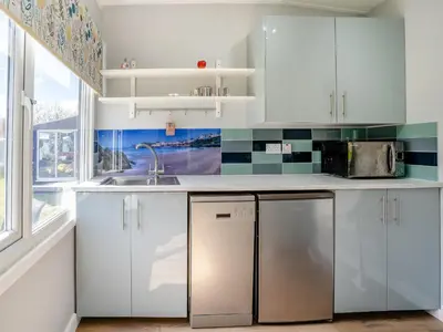 a kitchen with white cabinets and a sink and a window at Tynrhos Lake View in Cilcennin