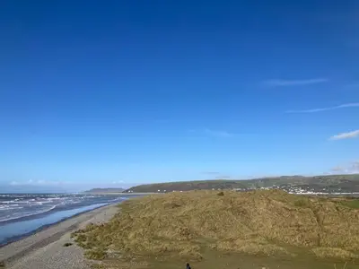a person standing on a beach next to the ocean at Bay View Lodge, Brynowen in Borth