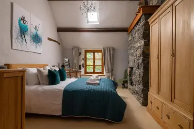 a bedroom with a bed and a stone wall at Ysgoldy in Llanfor
