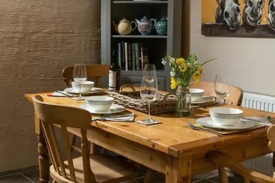 a wooden table with glasses and plates and flowers on it at Ysgoldy in Llanfor