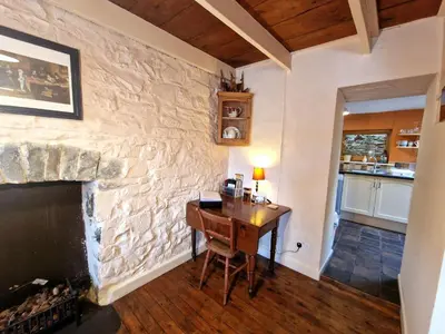 a room with a stone wall with a desk and a fireplace at Arwel in New Quay