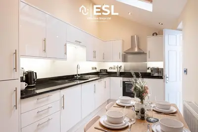 a kitchen with white cabinets and a wooden table at Super Central - Quiet - 2 Bedroom Cottage in Shrewsbury
