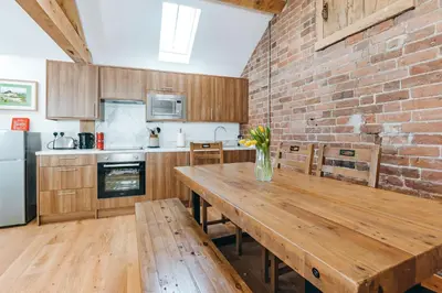 a kitchen with a wooden table and a brick wall at ryton grange church barn sleeps 5 in Shrewsbury