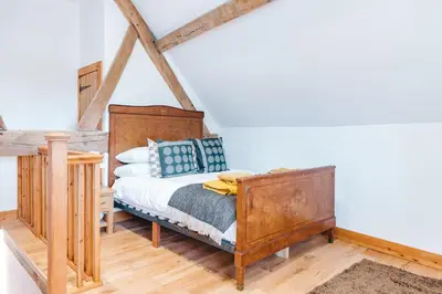 a bedroom with a bed and a wooden bed frame at ryton grange church barn sleeps 5 in Shrewsbury