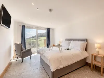 a bedroom with a bed and a chair and a window at Larchwood Lodge in Old Radnor