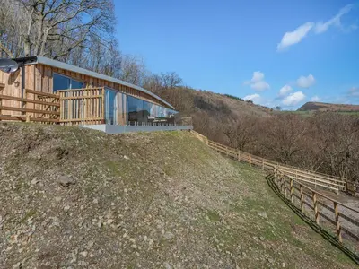 a house on top of a hill with a fence at Larchwood Lodge in Old Radnor