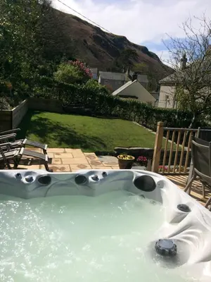a jacuzzi tub in the backyard of a house at Lovely cottage in Snowdonia, private hot tub, by mountains & award winning beach in Fairbourne