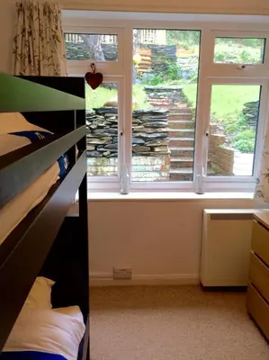 a bedroom with a window and a bed in front of it at Lovely cottage in Snowdonia, private hot tub, by mountains & award winning beach in Fairbourne