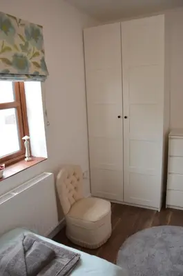a bathroom with a white cabinet and a chair at Stone Cottage in Shrewsbury