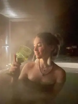 a woman sitting in a bathtub holding a glass at Luxury Lodge In The Treetops in Llanbrynmair