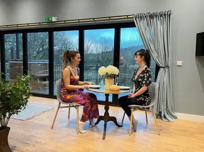 two women sitting at a table in a room at Luxury Lodge In The Treetops in Llanbrynmair