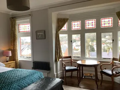 a bedroom with a bed and a table and windows at The Views Bed and Breakfast in Llangollen