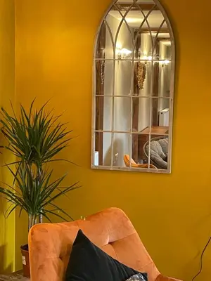 a yellow room with a couch and a mirror at The Grain Loft in Clun