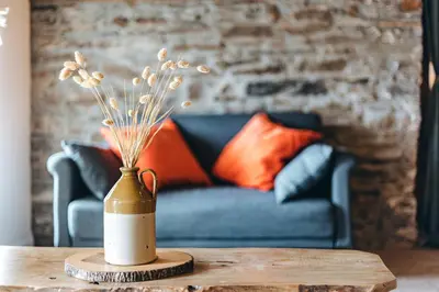 a vase with flowers on a table with a couch at The Grain Loft in Clun
