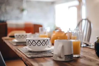 a wooden table with a cup and cups of orange juice at The Grain Loft in Clun