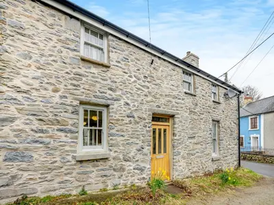 an old stone house with a yellow door at Ivy Bush Cottage in Llanddewi-Brefi