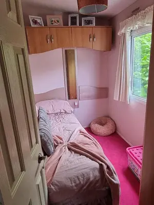 a bedroom with a bed in a pink room at Caravan - Sleeps 8 pet friendly & hot tub in Welshpool