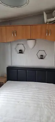 a bedroom with a bed with two mirrors on the wall at Caravan - Sleeps 8 pet friendly & hot tub in Welshpool