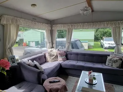 a living room with a purple couch and windows at Caravan - Sleeps 8 pet friendly & hot tub in Welshpool