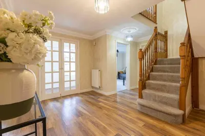 a living room with stairs and a vase of flowers at Spacious house in quiet cul-de-sac near to Hospital in Shrewsbury