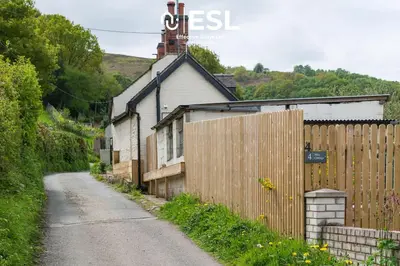 a house on a dirt road next to a fence at Luxurious 2 Bedroom Countryside Hot Tub Retreat in Stiperstones in Shelve