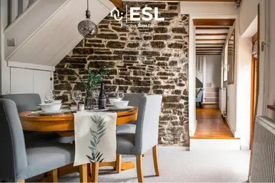 a dining room with a stone wall and a table and chairs at Luxurious 2 Bedroom Countryside Hot Tub Retreat in Stiperstones in Shelve