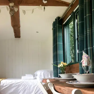a dining room with a table and a window at Shire the Shepherd's Hut at Pentref Luxury Camping in Penuwch