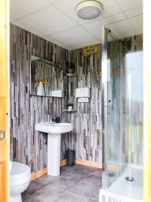 a bathroom with a sink and a toilet and a shower at Shire the Shepherd's Hut at Pentref Luxury Camping in Penuwch