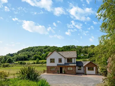 a house in a field with a hill in the background at Dyffryn Cain in Aberystwyth