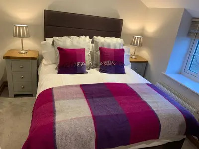 a bedroom with a large bed with purple and red pillows at Broombush B & B & Yr Nyth Shepherds Hut in Aberhafesp