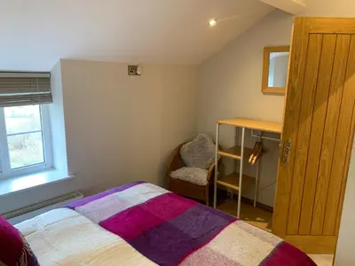 a small bedroom with a bed and a chair at Broombush B & B & Yr Nyth Shepherds Hut in Aberhafesp