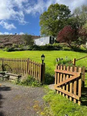 a wooden fence in a yard with a field at Broombush B & B & Yr Nyth Shepherds Hut in Aberhafesp