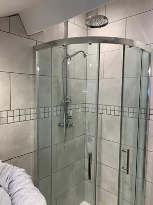 a shower with a glass door in a bathroom at Broombush B & B & Yr Nyth Shepherds Hut in Aberhafesp