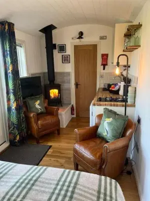 a room with two chairs and a room with a fireplace at Broombush B & B & Yr Nyth Shepherds Hut in Aberhafesp