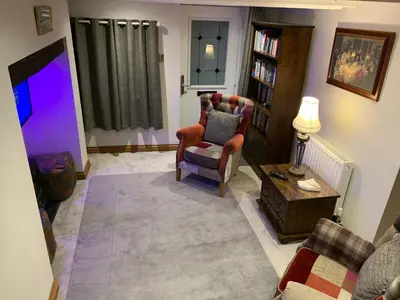 a living room with a couch and a chair and a tv at Broombush B & B & Yr Nyth Shepherds Hut in Aberhafesp