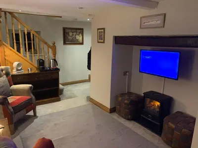 a living room with a fireplace and a flat screen tv at Broombush B & B & Yr Nyth Shepherds Hut in Aberhafesp