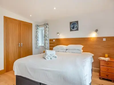 a bedroom with a large white bed with two towels at Bodwennol - a stunning house! in Aberdyfi