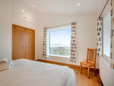 a bedroom with a bed and a window and a chair at Bodwennol - a stunning house! in Aberdyfi