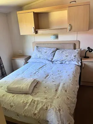 a bedroom with a bed with a white comforter at Van number 123 Beautiful Caravan sleeps 4 in Aberystwyth