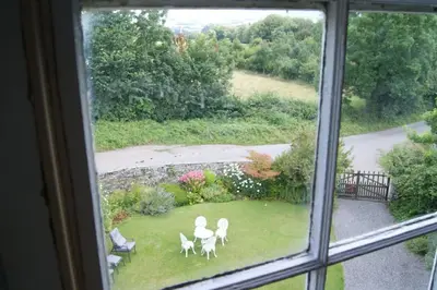 a window view of a garden with white chairs in the yard at Top Floor at Cantref House in Brecon