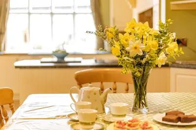a table with a vase of yellow flowers and cookies at Llanhedric House in Clun