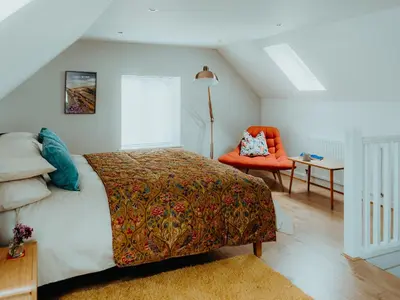 a bedroom with a bed and an orange chair at The Coach House Barn in Shrewsbury